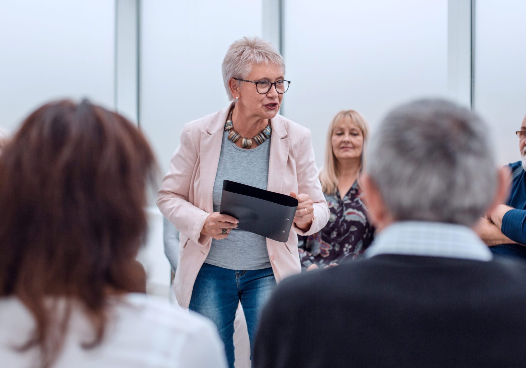 Businesswoman presenting to an audience, with a focus on engagement and communication skills, in a modern conference setting.